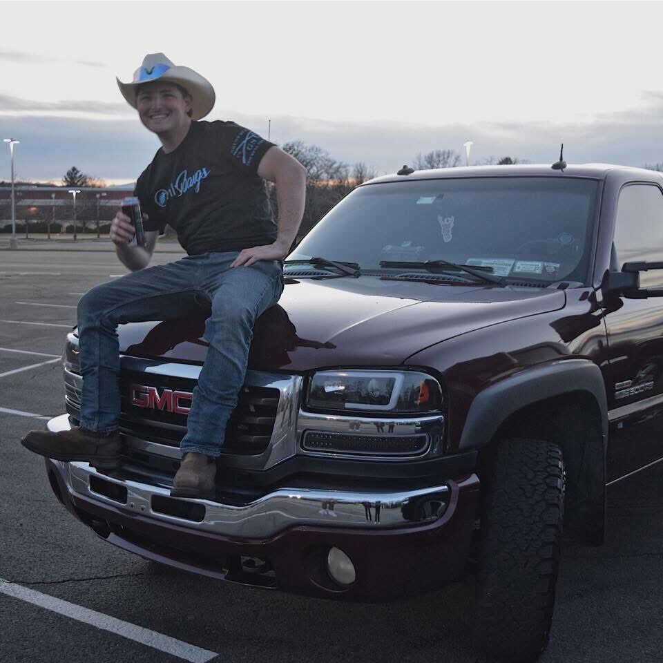 Mason in his cowboy hat on the hood of his GMC